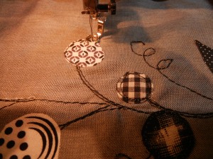 Next, I added circle and leaf shapes: pulling from my black and white fabrics, with Wonder-Under to fuse, a lighter-weight thread to outline and secure.